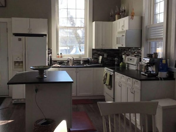 A modern kitchen with white cabinets, a black countertop, and a window providing natural light.