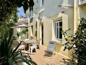 A sunlit outdoor patio with a table and chairs, surrounded by plants and a white fence. - Ref 536 - Ground floor classified 2** of a charming villa (SOULAC SUR MER)