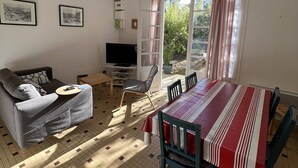 Una sala de estar con sofá, televisión, mesa de comedor y sillas.