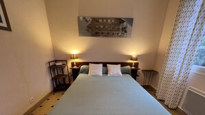 Una habitación de hotel con una cama grande, dos mesitas de noche con lámparas, un cabecero de madera y un cartel sobre la cama.