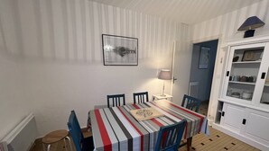 Un comedor con mantel a rayas, sillas azules, una lámpara y un aparador con vajilla.