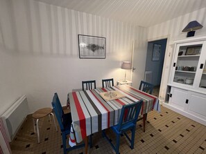 A dining area with a striped tablecloth, blue chairs, a lamp, and a cabinet with dishes.