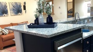 Een moderne keuken met een granieten aanrecht, een roestvrijstalen vaatwasser en een plafondventilator.