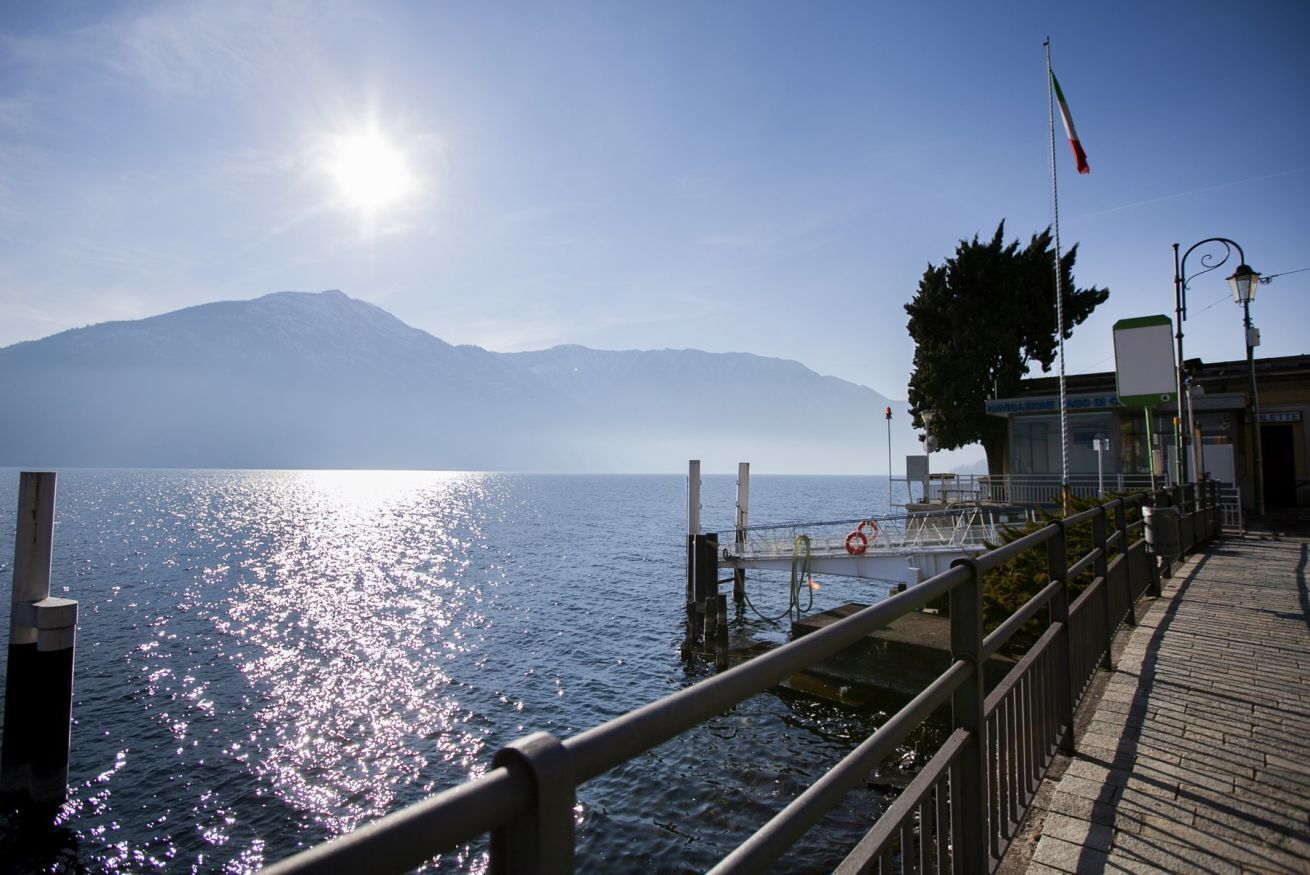 A waterfront scene with a dock, a mountain in the background, and a clear sky.