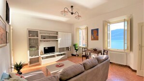 Una sala de estar con sofá, televisor y un comedor con mesa y sillas.
