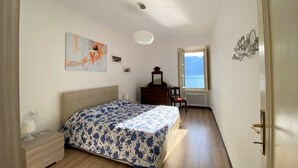 Un dormitorio con cama, cómoda, espejo y ventana con vista al mar.