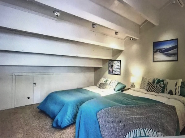 A bedroom with a bed, pillows, a wall-mounted artwork, and a ceiling light fixture.