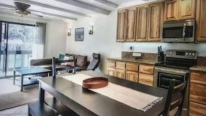 A modern kitchen with wooden cabinets, a microwave, and an oven. There is a dining area with a table and chairs. - Boreal condo 3 bed 2 bath near Boreal, Soda Springs on Boreal Lake & near Donner (Truckee)