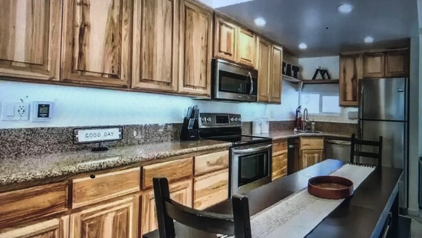 A modern kitchen with wooden cabinets, stainless steel appliances, and a central island with seating. - Boreal condo 3 bed 2 bath near Boreal, Soda Springs on Boreal Lake & near Donner (Truckee)