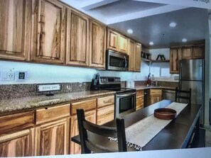 A modern kitchen with wooden cabinets, stainless steel appliances, and a central island with seating.