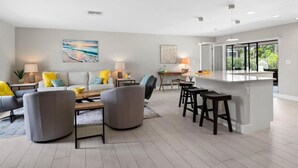 A modern living room with a sofa, coffee table, and a dining area with a bar. - Private Naples Oasis w/ Cart, Gym & Saltwater Pool (Naples)