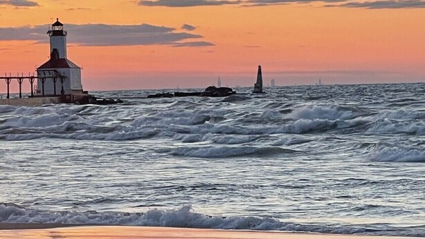 Een vuurtoren bij zonsondergang met ruwe zeegolven.