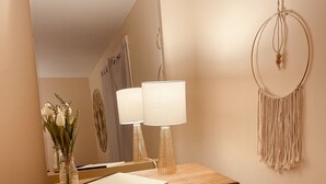 Een houten opbergkast met spiegel, twee lampen en een macramé wanddecoratie.
