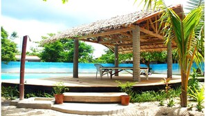 A covered outdoor area with a pool, wooden deck, and seating. - Purple Snapper Dive Resort - Hostel/backpacker Accommodation (Daanbantayan)