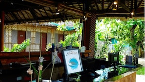 A reception desk with a framed sign, a cash register, and a coffee machine. - Purple Snapper Dive Resort - Hostel/backpacker Accommodation (Daanbantayan)