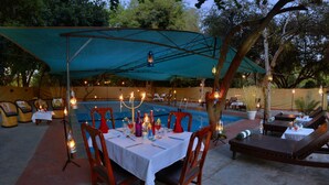 Ein Außenbereich mit Essbereich, Tischen, Stühlen, einem Pool und Liegemöglichkeiten.