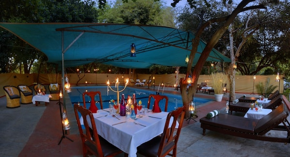 An outdoor dining area with tables and chairs, a pool, and lounge seating.