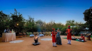 An outdoor dining area with a fire pit, chairs, and tables arranged for guests. - Abrar Palace & Jungle Camps (Sawai Madhopur)