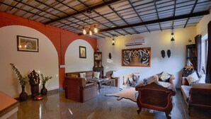 Ein geräumiges Wohnzimmer mit hoher Decke, Kamin und verschiedenen Sitzgelegenheiten.