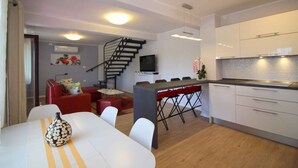 Une cuisine moderne avec des armoires blanches, une cuisinière encastrée et un coin repas comprenant une table et des chaises.