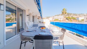 A balcony with a table set for dining, chairs, and a view of the city. - 1-Br Apartment, Sea View Terrace & Parking (Cannes)