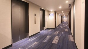 A hotel hallway with elevators, a carpeted floor, and a sign on the wall. - Sapporo Washington Hotel Plaza (Sapporo)
