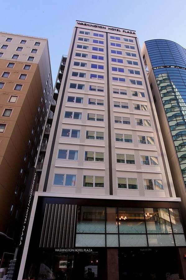 Um edifício alto de hotel com fachada moderna, vários andares e um letreiro chamativo no topo.