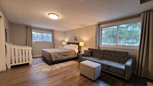 A bedroom with a bed, a sofa, a small table, and a window. - Door County Cottage, near Haines Beach! (Sturgeon Bay)