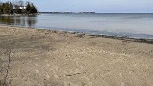 A beach with a sandy shore and a calm body of water. - Door County Cottage, near Haines Beach! (Sturgeon Bay)