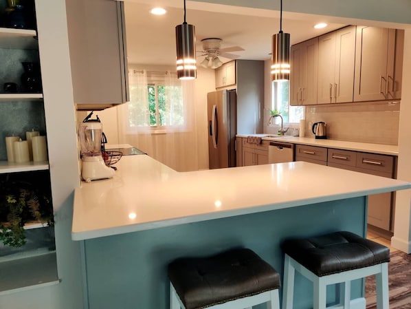 A modern kitchen with a large island, pendant lights, and built-in appliances.