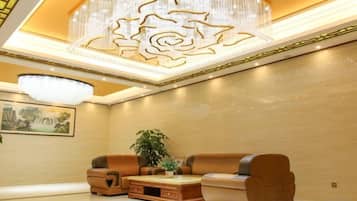A modern interior with a chandelier, sofas, and a painting on the wall.