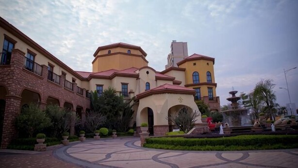 Un patio con una fuente, un edificio con varios arcos y un cielo despejado.