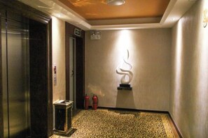 Un pasillo con suelo estampado, un extintor y una escultura en la pared.