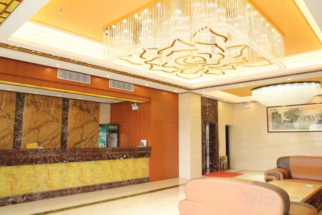 Un hall de hotel con mostrador de recepción, zona de estar y una lámpara de araña.