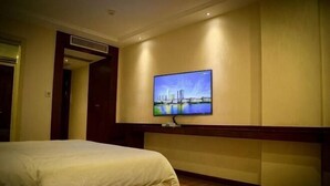 Una habitación de hotel con cama, televisión montada en la pared y suelo de madera.