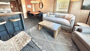 Un salon moderne avec un canapé, une table basse et des tabourets de bar.