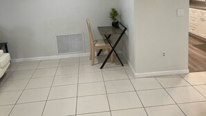 A room with a tiled floor, a dining table with chairs, a potted plant, and a vent on the wall. - A Great Boca Home Stay (Boca Raton)