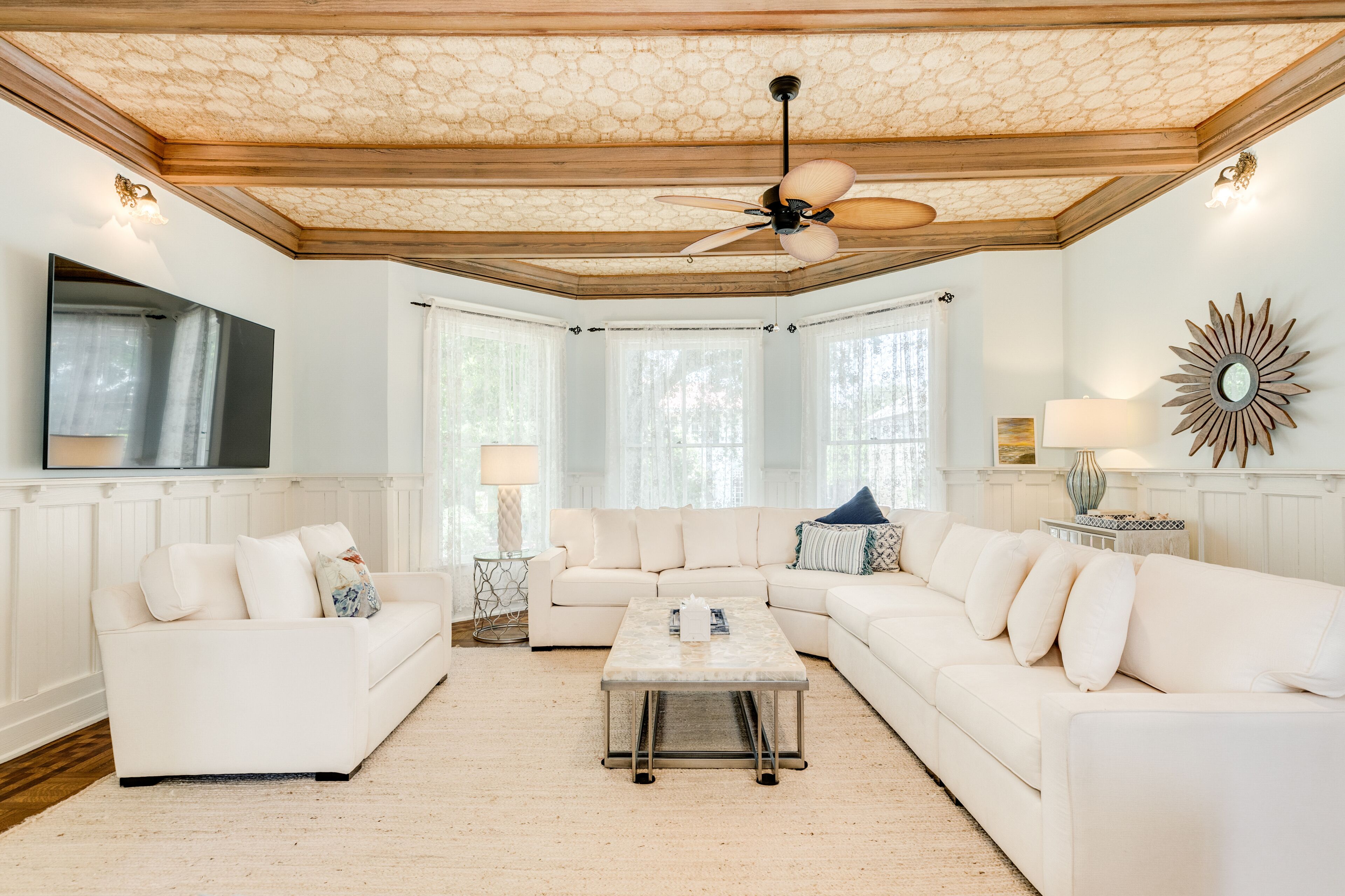 A spacious living room with a large white sectional sofa, a coffee table, and a ceiling fan.