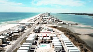 An aerial view of a coastal area with a beach, buildings, and a marina. - The Sand Haus - Steps to Beach - 7 Separate Beds - Pet Friendly - Pool - Grill (Gulf Shores)