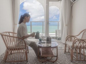A person sitting at a table with a view of the ocean through large windows.