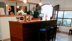 A kitchen with a wooden island, bar stools, pendant lights, and a large window. - Pousada Arvore Da Vida (Teresópolis)