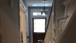 A hallway with wooden flooring, white walls, and a staircase with white railings. - Brookland Quiet Living (Washington)