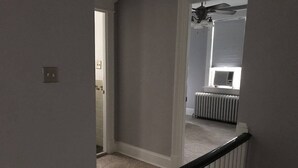 A hallway with a white railing, a door leading to another room, and a radiator in the background. - Brookland Quiet Living (Washington)