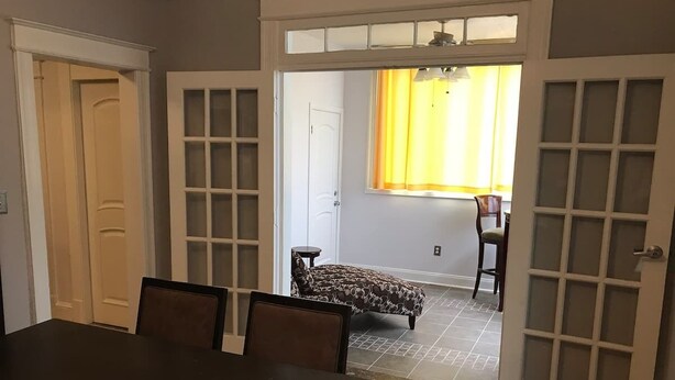 A dining area with a dark wooden table and chairs, a patterned ottoman, and a view of a patio with a chair and a table. - Brookland Quiet Living (Washington)