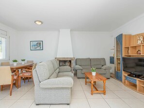 A modern living room with a fireplace, sofa, TV stand, and dining area.