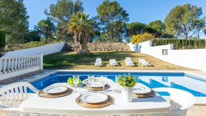 A poolside dining area with a table set for four, surrounded by white chairs. - Beautiful private villa for 6 guests with WIFI, private pool, TV and pets allowed (L'escala)