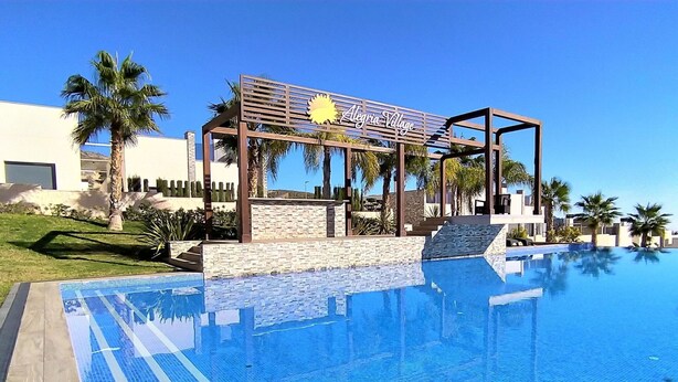 Uma piscina com um pergolado e uma placa com a inscrição 'Alegia Village'.