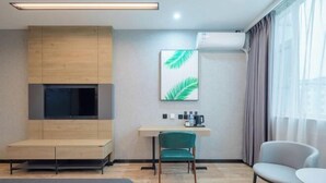 Une chambre d’hôtel moderne, équipée d’un lit, d’un bureau avec une chaise, d’une télévision et d’une grande fenêtre avec des rideaux.