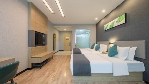 Une chambre d’hôtel moderne dotée d’un grand lit, d’une télévision, d’un banc et d’une œuvre d’art accrochée au mur.