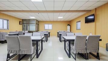 Un salón de conferencias con mesas y sillas dispuestas para reuniones.